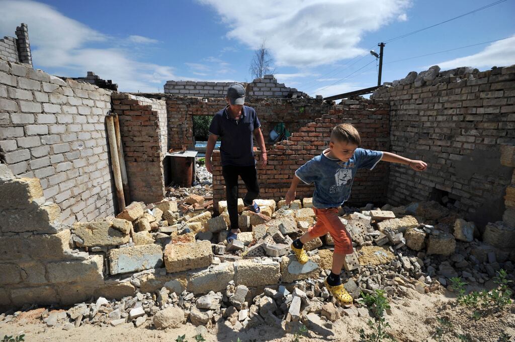 A man and a child walk amid debris of a house, destroyed during battles in the village of Velyka Dymerka, northeast of Kyiv, Ukraine. Photograph: Sergei Chuzavkov/AFP