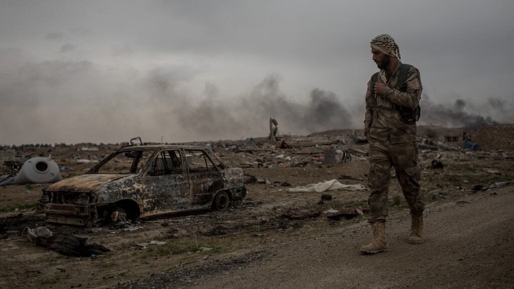 A Syrian Democratic Forces (SDF) fighter walks past destroyed vehicles in the final Islamic State encampment in Baghouz on Sunday. Photograph: Chris McGrath/Getty Images
