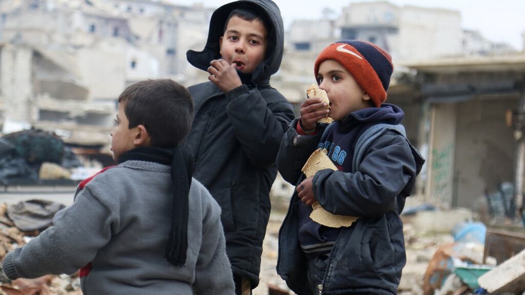 Boys eat bread as they wait to be evacuated from a rebel-held sector of eastern Aleppo. Photograph: Abdalrhman Ismail/Reuters