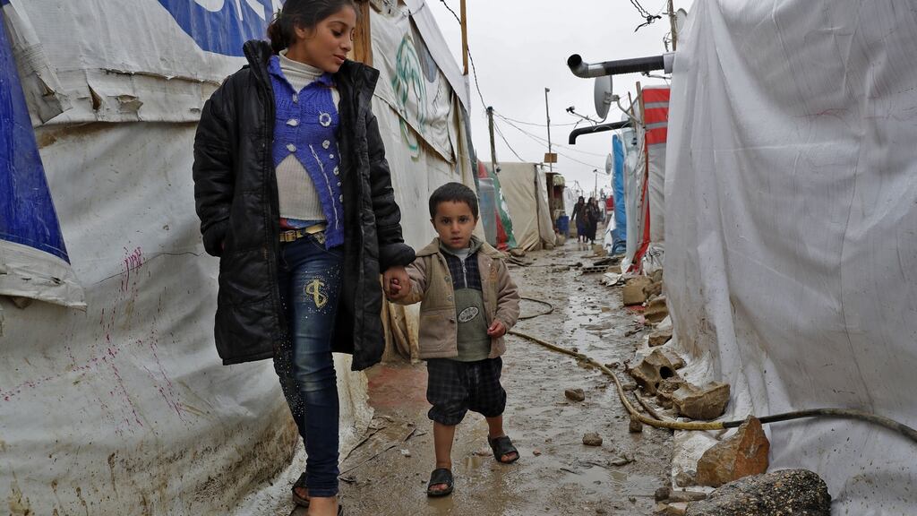 Syrian refugee children walk in a muddy alley at an unofficial refugee camp in the village of Deir Zannoun in Lebanon’s Bekaa valley on January 31, 2017. / AFP / JOSEPH EID