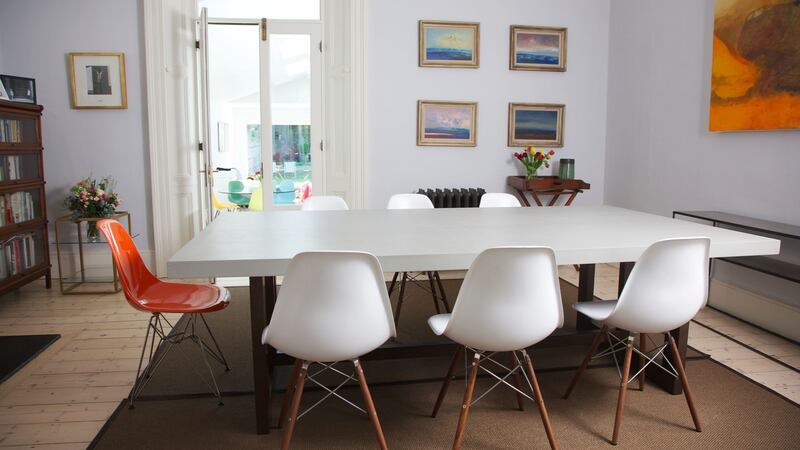 Interconnecting with the living room a set of French doors lead down into the large open plan kitchen. Eames-style chairs in white and orange surround an antique dining table. Photograph: Emily Quinn
