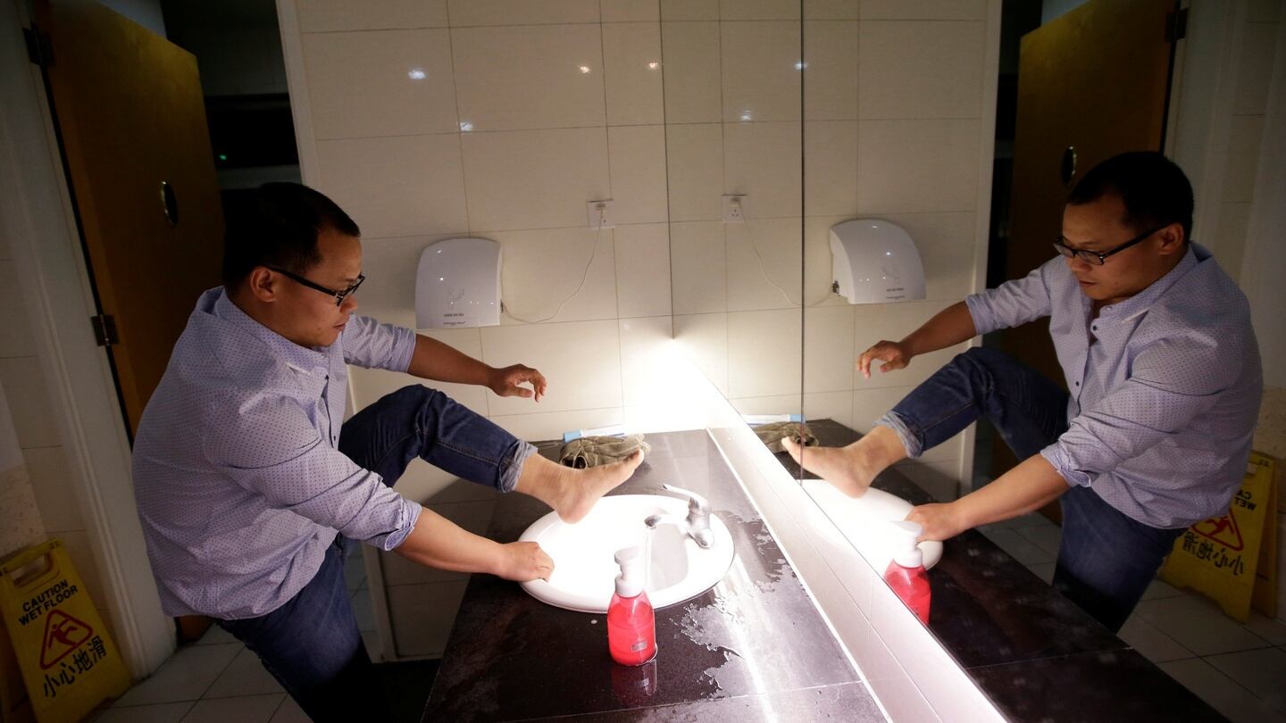 Liu Zhanyu, a client manager at DouMiYouPin, washes his feet at the office’s bathroom before going to sleep after finishing work at midnight. Photograph: Jason Lee
