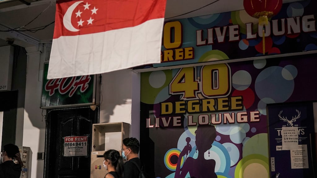 A couple walks under a Singapore flag hanging outside a karaoke lounge in Singapore on Friday. Photograph: Wallace Woon/EPA