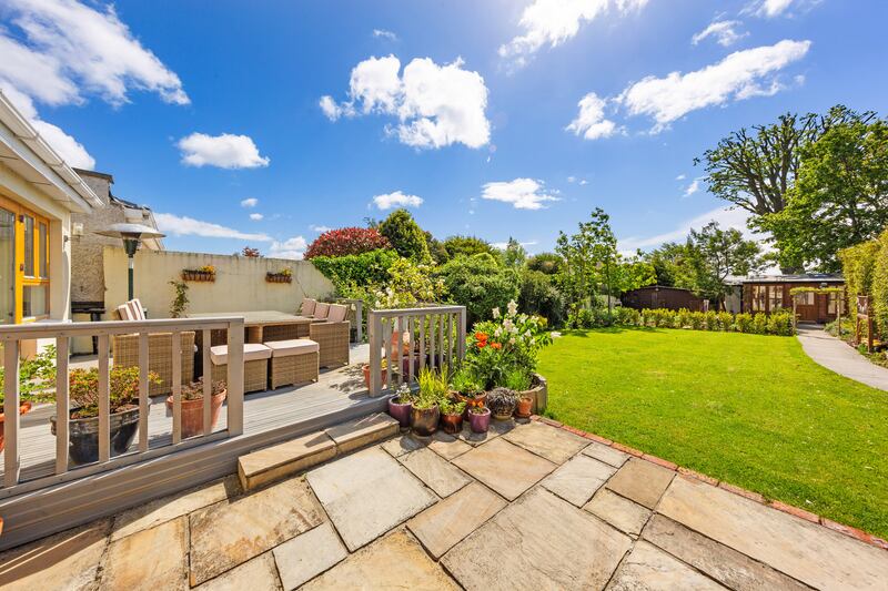 The rear decking leads down to a stone patio and well-tended lawn.