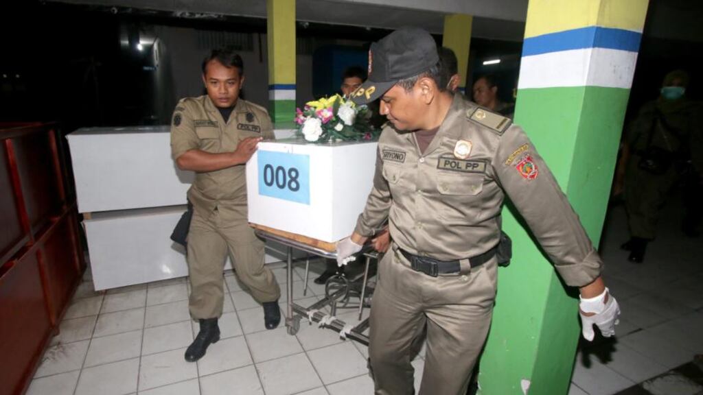 Indonesian officers wheel in a temporary coffin carrying  a victim of the  AirAsia plane crash. Photograph: Wahyudin/EPA.