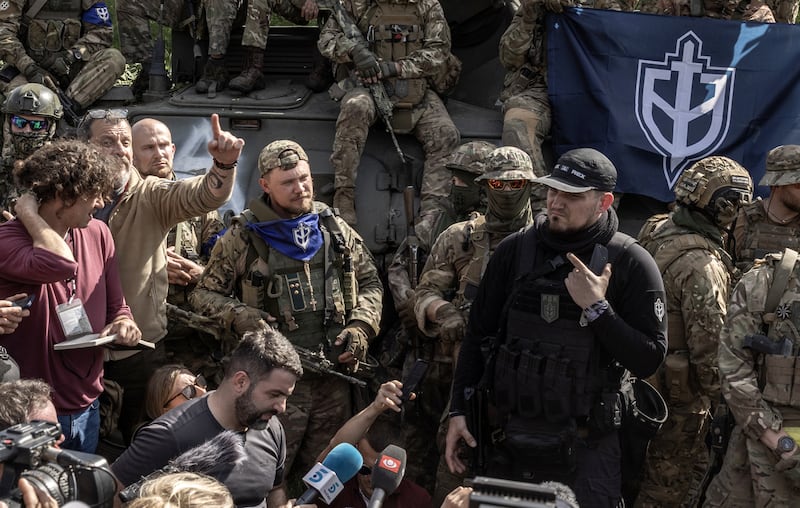 Denis Kapustin, in black, is interviewed and photographed by reporters in the northeastern Ukraine in May 2023. The RDK founder has been a prominent figure in Russian and German football hooligan and far-right mixed martial arts communities. Photograph: Finbarr O’Reilly/New York Times