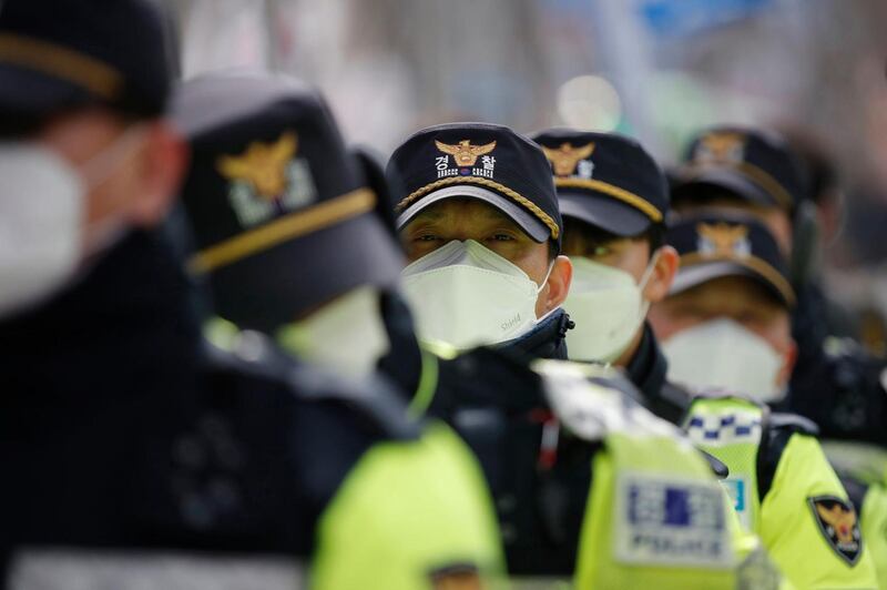 Police officers wearing face masks stand guard during a rally in downtown Seoul, South Korea. Photograph: Lee Jin-man/AP