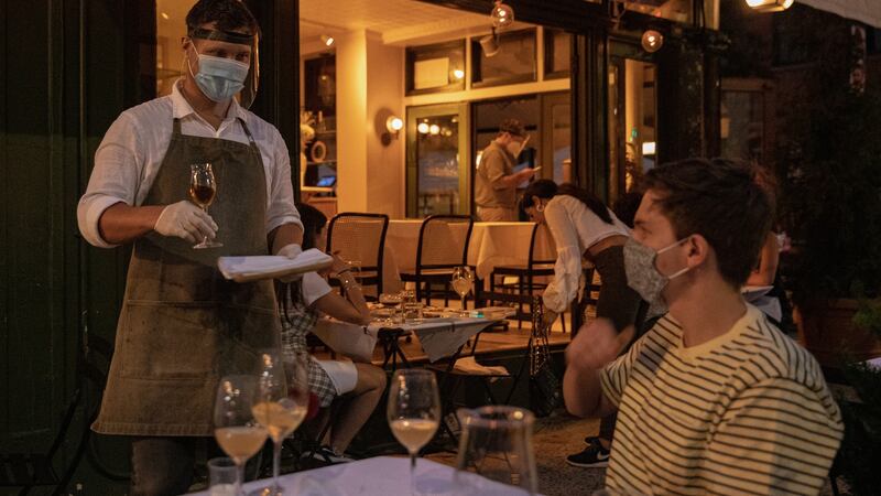 A waiter wearing personal protective equipment serves a customer outside King restaurant in the West Village in New York. Photograph: The New York Times