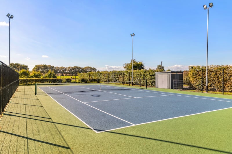 Floodlit tennis court with storage shed