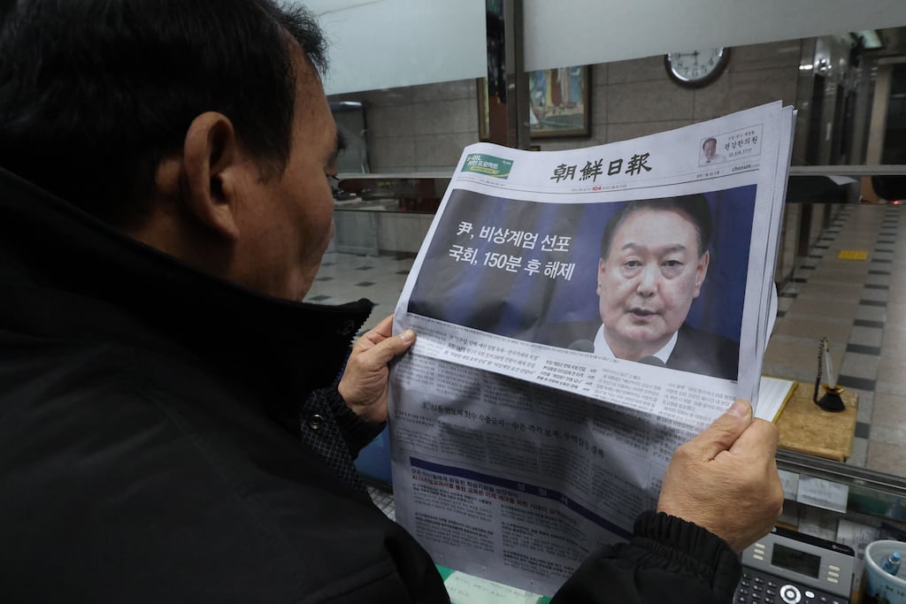 A man in Seoul, South Korea, lookings at a newspaper reporting President Yoon Suk Yeol announcing his intention to lift emergency martial law. Photograph: EPA