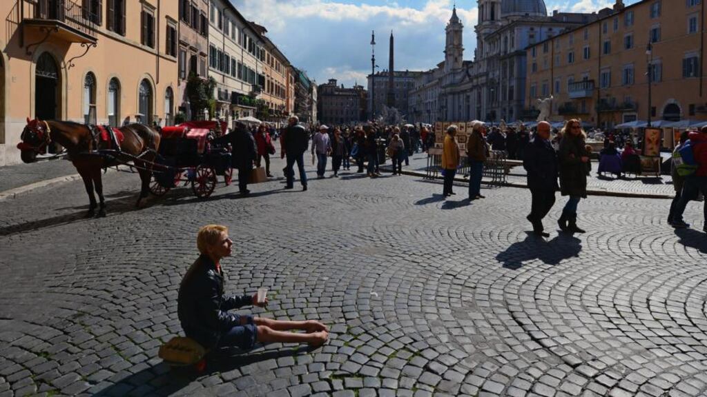 A woman sits on the ground begging for money in Piazza Navona in Rome. Photograph: Jeff J Mitchell/Getty Images