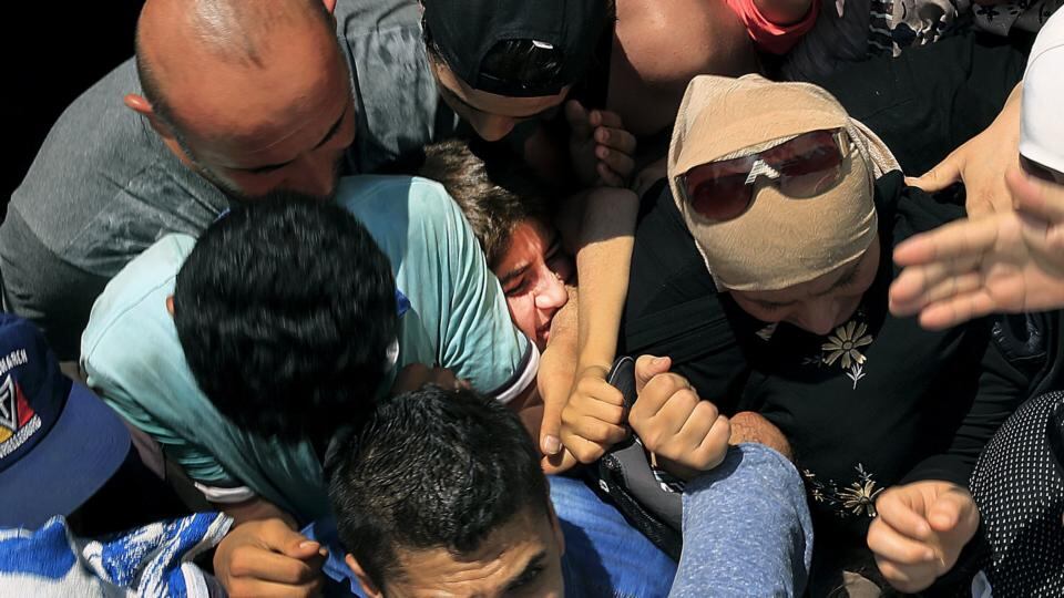 A Syrian refugee girl is squashed as other clash during registration procedure in the national stadium. Photograph: Yannis Behrakis/Reuters
