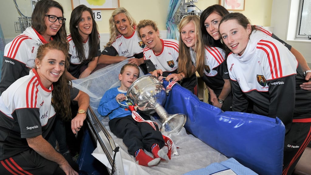 Eoin O’Brien (6), from Shannon, Co Clare, with Cork footballers (L-R) Aisling Hutchings, Sinead Cotter, Ciara O’Sullivan, Brid Stack, Valerie Mulcahy, Roisin Phelan, Aisling Barret and Aine Terry during a visit by the champions to Temple Street Hospital, Dublin. Photograph: Sam Barnes/Sportsfile