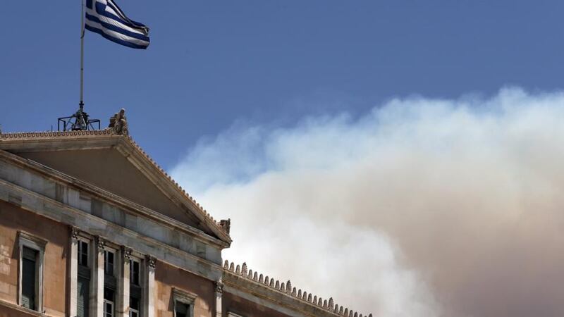 A Greek national flag flutters atop the parliament building as smoke from wildfire rises in Athens, Greece, July 17th, 2015. Photograph: Alkis Konstantinidis/Reuters