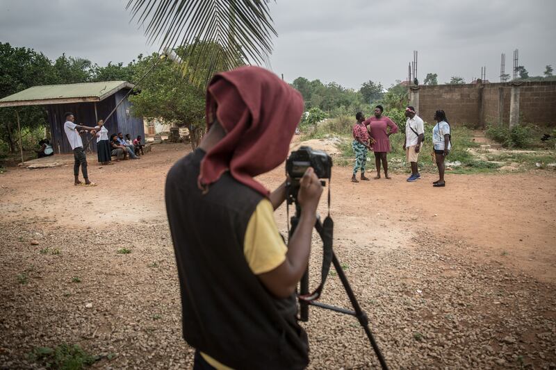 On set with a film crew in Kumasi, the capital of Ghana's Ashanti Region. The cameraman has a jumper over his head to keep the monitor visible in the blazing sun. Photograph: Sally Hayden