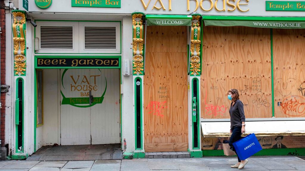 A woman wearing a protective face covering walks past a boarded-up bar in Dublin. Photograph: Paul Faith/AFP via Getty Images