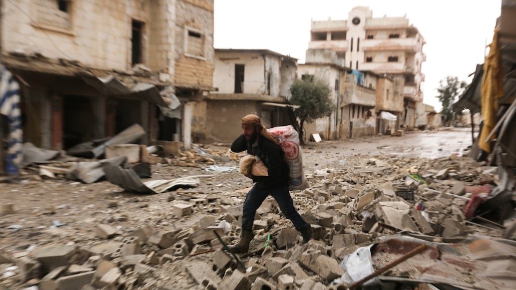 A man carries his belongings through a street destroyed in recent bombings by the Syrian government forces in the town of Sarmin, in Idblib province, Syria. Photograph: Ghaith Alsayed/AP