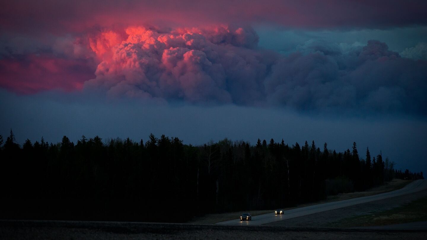 Motorists travel south on Alberta Highway 63 as the setting sun illuminates a huge plume of smoke. Photograph: Darryl Dyck/Bloomberg
