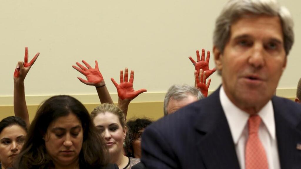 Protesters hold red hands up as US secretary of state John Kerry speaks before the House Foreign Affairs Committee on Capitol Hill in Washington today.  President Barack Obama  issued a blunt challenge to sceptical US lawmakers today to approve his plan for a military strike on Syria, saying inaction would put America’s prestige and their own credibility at risk. Photograph: Doug Mills/The New York Times
