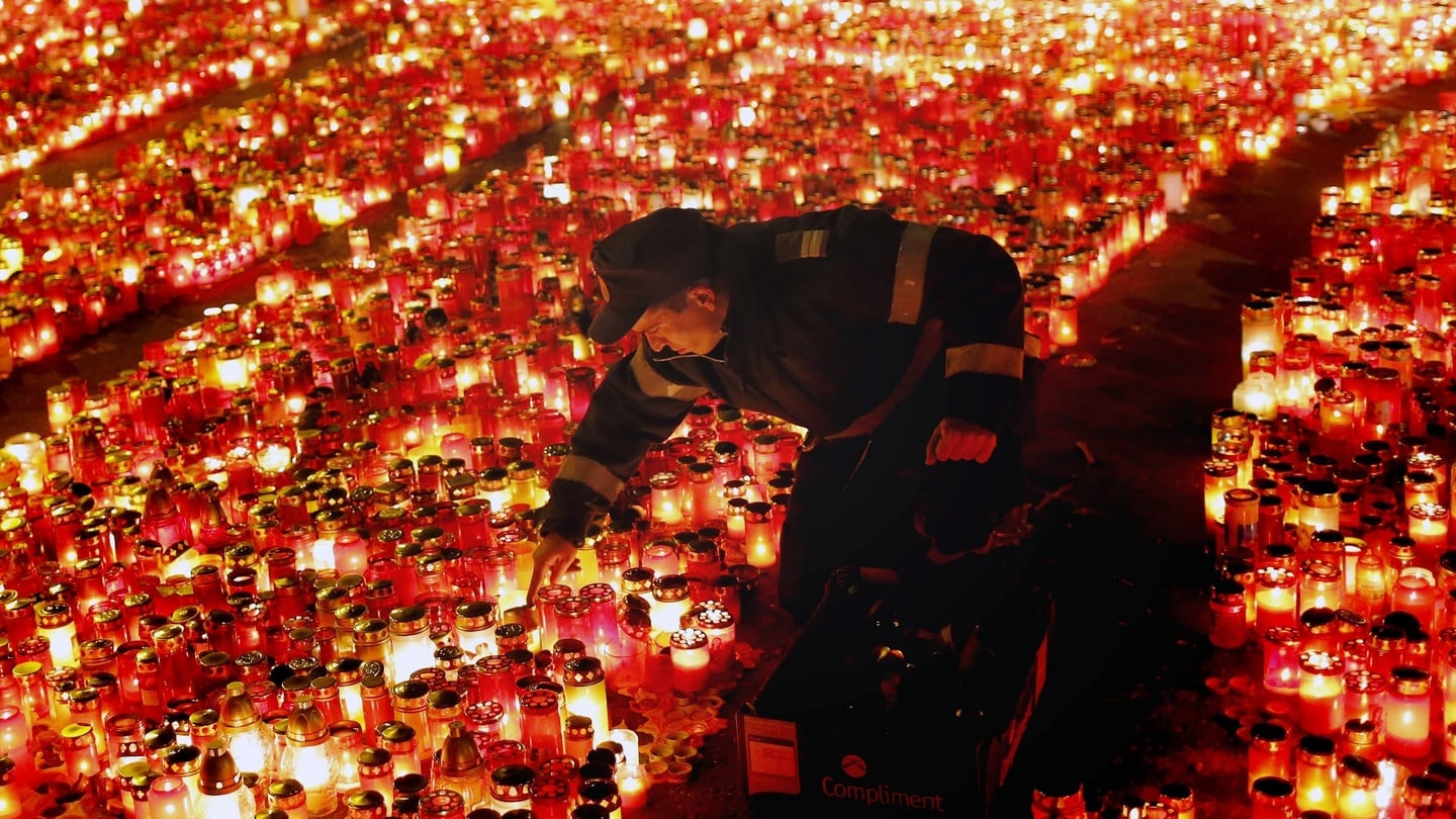 A Romanian policeman arranges  candles placed by the visiting people who came to pay their respects for the night club fire victims. Photograph: EPA