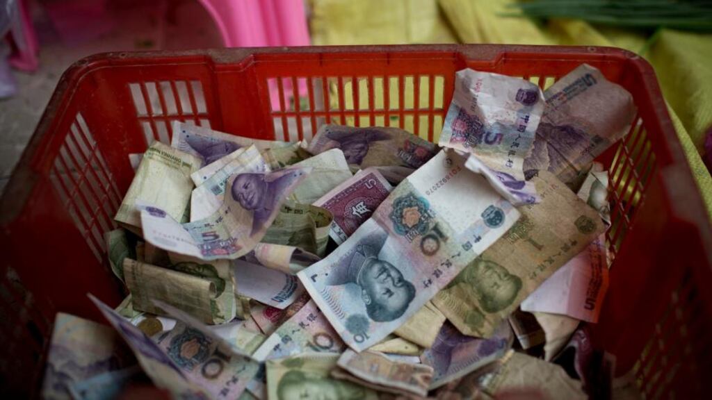 Chinese yuan banknotes sit in a container at a stall at the Shekou wet market in Shenzhen, China