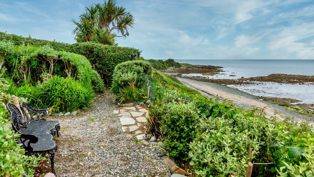 The garden rolls down to a sandy beach