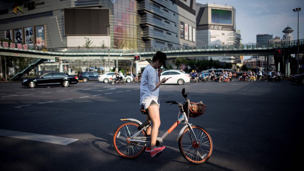 A cyclist uses a smartphone in Shanghai on July 3rd. A Dutch telecom company has developed a new app that shuts down your mobile phone signal once you unlock and mount your bike. File photograph: Johannes Eisele/AFP/Getty Images