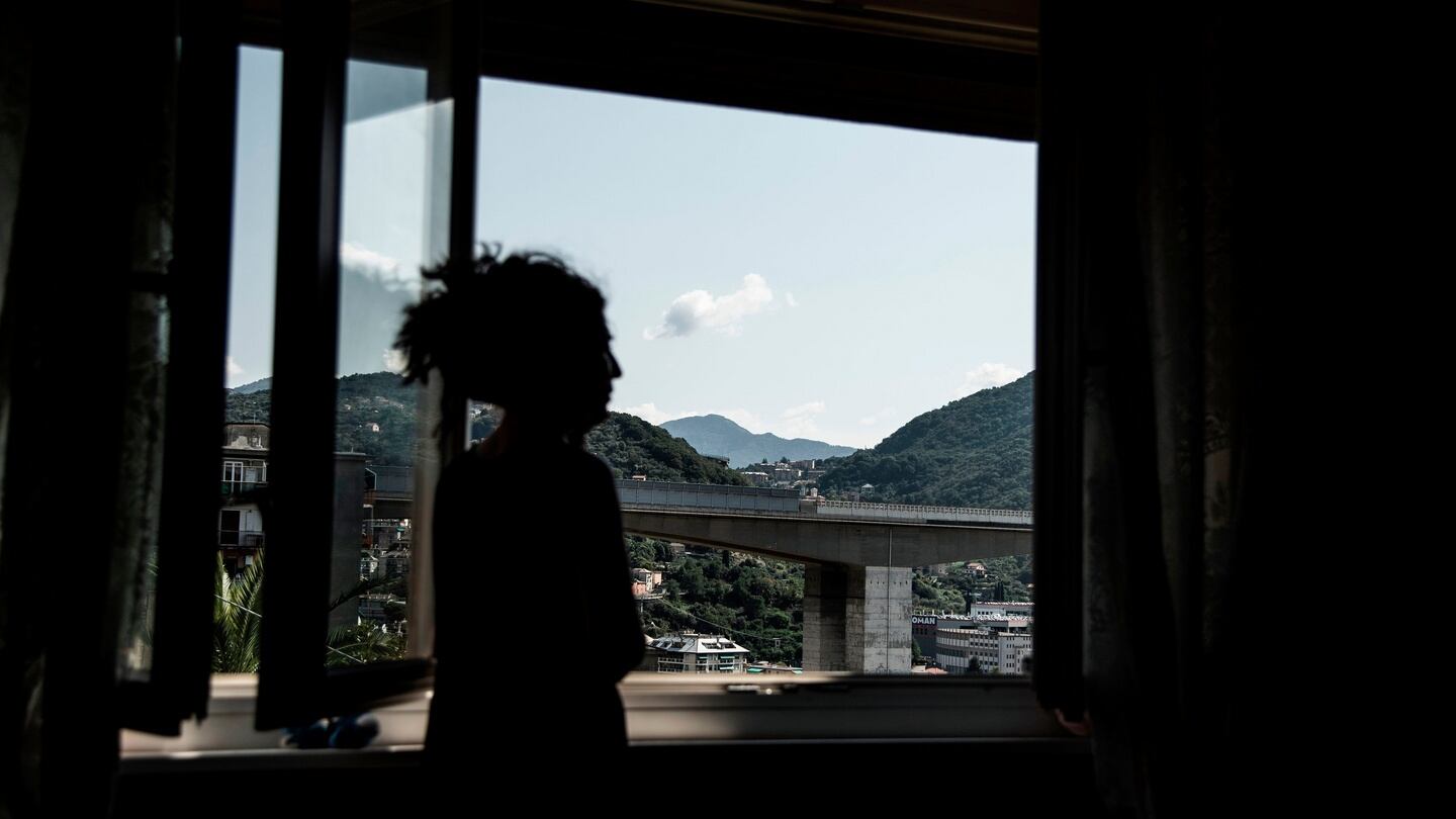 A woman looks from her window towards the E80 highway bridge of Staglieno in Genoa. Photograph: Marco Bertorello/AFP/Getty