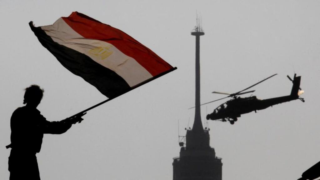 An opponent of Egypt’s ousted president Mohammed Morsi waves a national flag as a military helicopter flies over Tahrir Square in Cairo. Photograph: Amr Nabil/AP