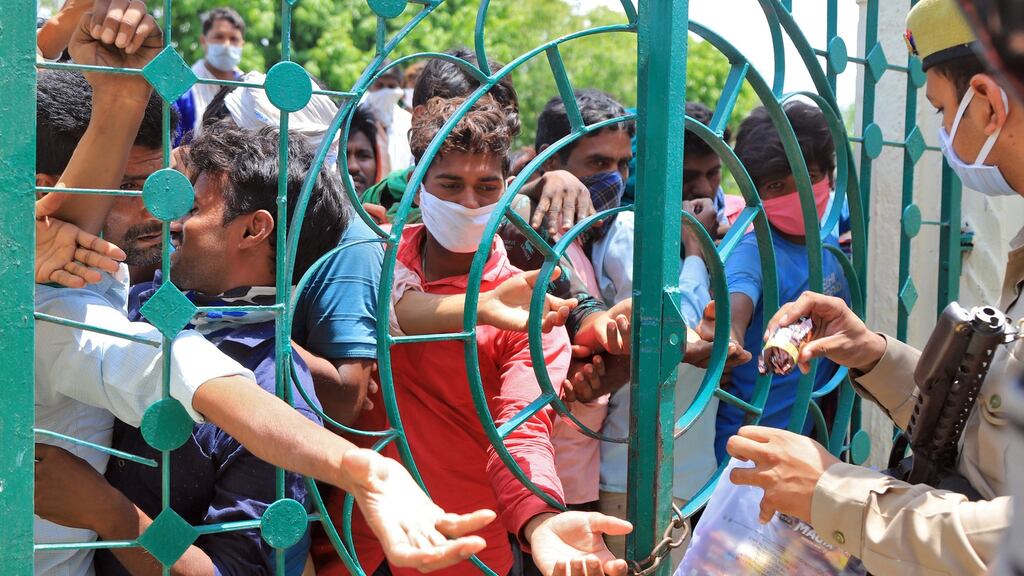 Migrant workers, who were stranded in the central state of Madhya Pradesh, India due to the lockdown, huddle to receive biscuit packets distributed by police. Photograph:  Reuters/Jitendra Prakash