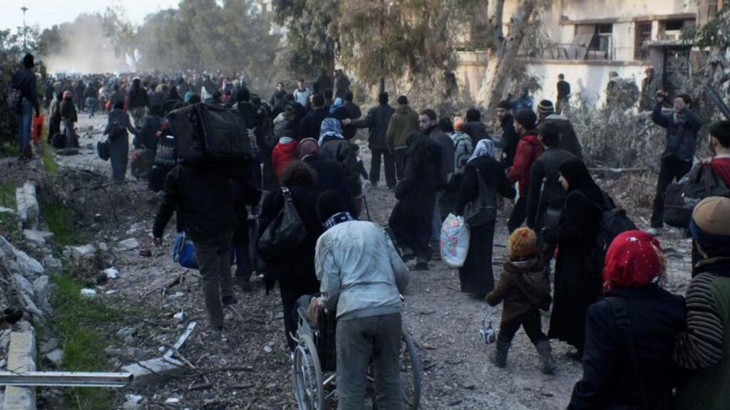 Civilians carry their belongings as they walk towards a meeting point to be evacuated from a besieged area of Homs. Photograph: Yazan Homsy/Reuters