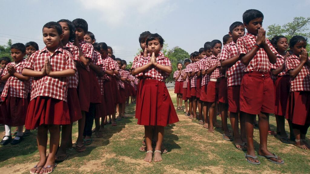 Schoolchildren pray for the victims of the fire in the Hindu Puttingal temple in Kollam district, India, at their school in Agartala. Photograph: Jayanta Dey/Reuters