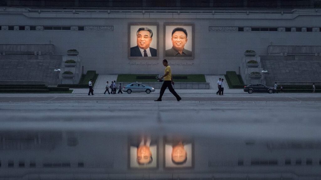 Pedestrians and vehicles pass before portraits of late North Korean leaders Kim Il-Sung (left) and Kim Jong-Il in Pyongyang. Photograph: Ed Jones AFP/Getty Images