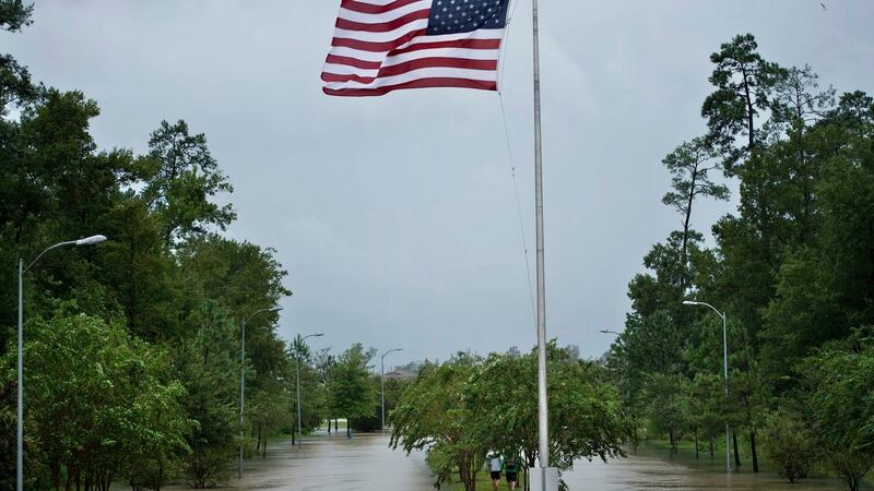 People walk along a flooded road’s median during the aftermath of Hurricane Harvey in Houston, Texas. Photograph: Brendan Smialowski/AFP/Getty Images