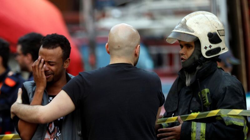 Firefighters comfort a man near the site where a building collapsed in downtown Sao Paulo, Brazil. Photograph: Leonardo Benassatto/Reuters