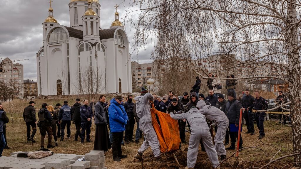Investigators and cemetery workers exhume the burned remains of a family, in Bucha, Ukraine. Photograph: Daniel Berehulak/The New York Times