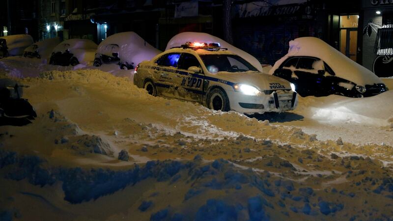 A New York City police car is seen driving past snow covered cars on the Lower East Side of Manhattan on Sunday. Photograph: Jason Szenes/EPA