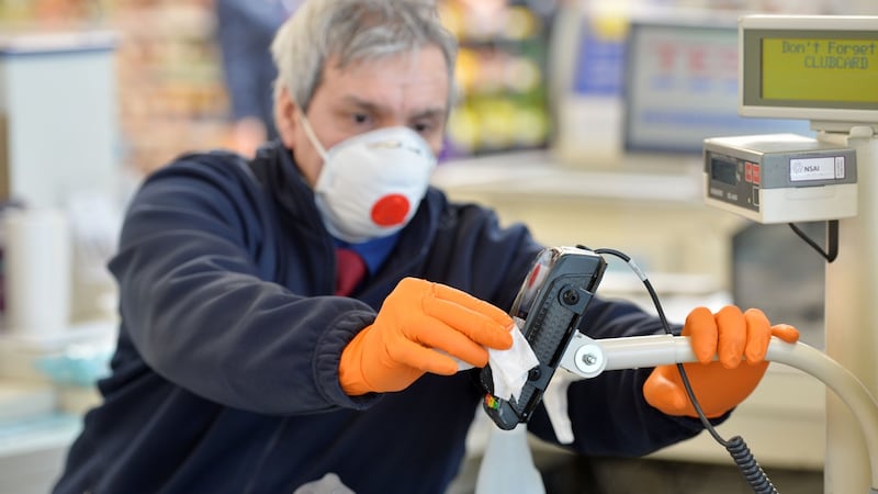 Gustavo Zamudio cleaning his checkout area and card machine between shoppers. Photograph: Alan Betson