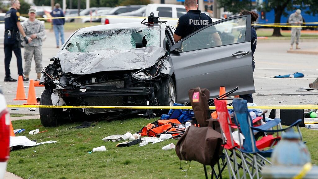 Police investigate a damaged car after the vehicle crashed into a crowd of spectators during the Oklahoma State University homecoming parade.