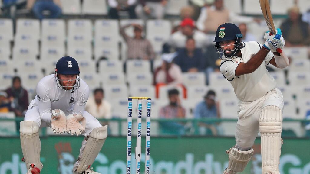 India’s Cheteshwar Pujara plays a cover drive for a boundary as England’s wicket-keeper Jonny Bairstow watches on the fourth day of their third cricket test match in Mohali, India. Photo: PA