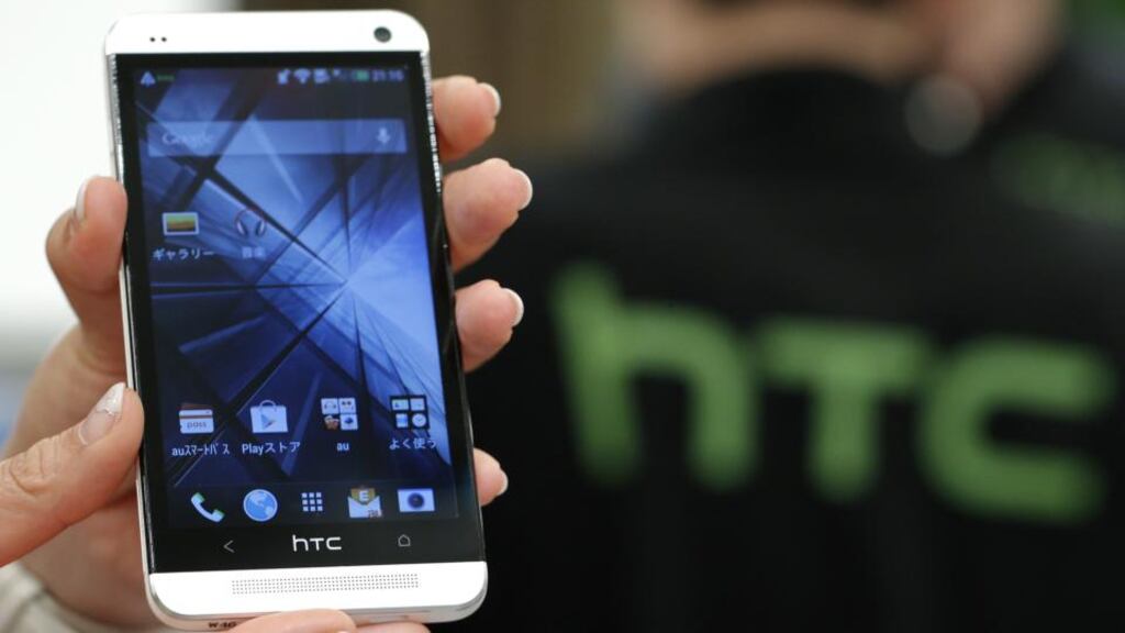 An employee displays a HTC smartphone. Some HTC employees were detained by Taiwan authorities after the smartphone maker alleged that some of its trade secrets were breached. Photo: Bloomberg
