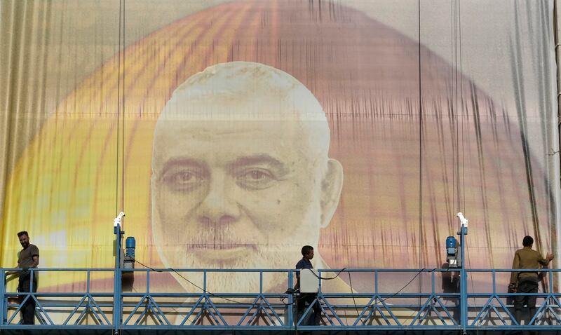 Iranian workers install a huge banner on a wall showing a portrait of Hamas leader Ismail Haniyeh Photograph: AP