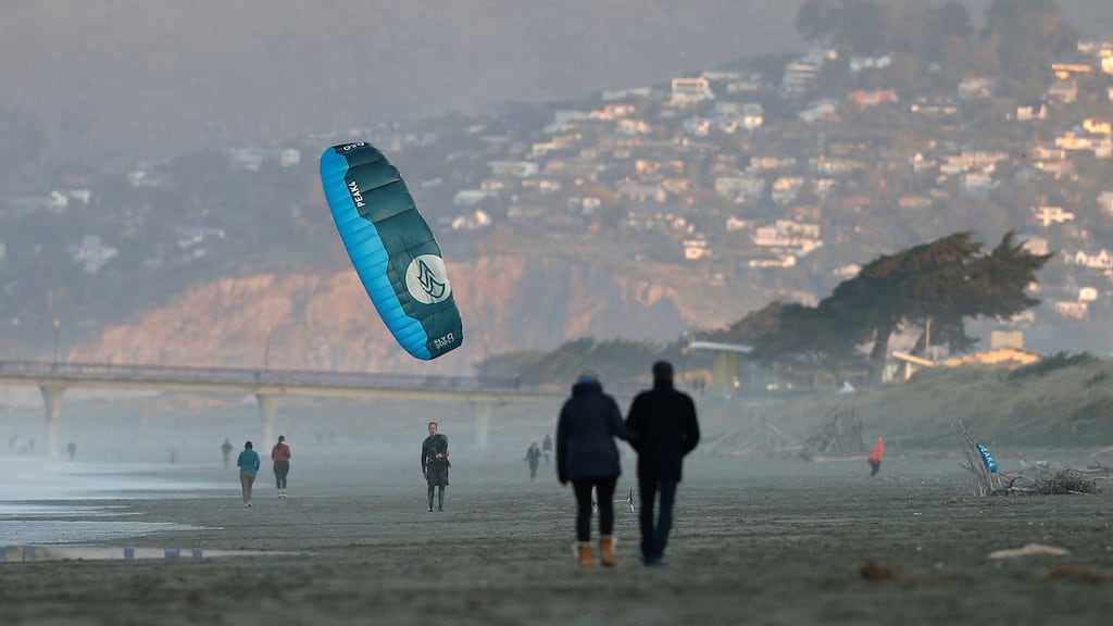 A windsurfer reels in his kite at New Brighton Beach in Christchurch, New Zealand on Tuesday after Cabinet agreed to remove almost all remaining coronavirus restrictions from midnight, Monday with the exception of the border structures. Photograph: Mark Baker/AP