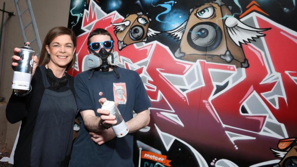 Lisa Comerford, Meteor’s head of brand and communications, with graffiti artist Omin at his half of the “Meteor Crawl Wall” in Dublin.