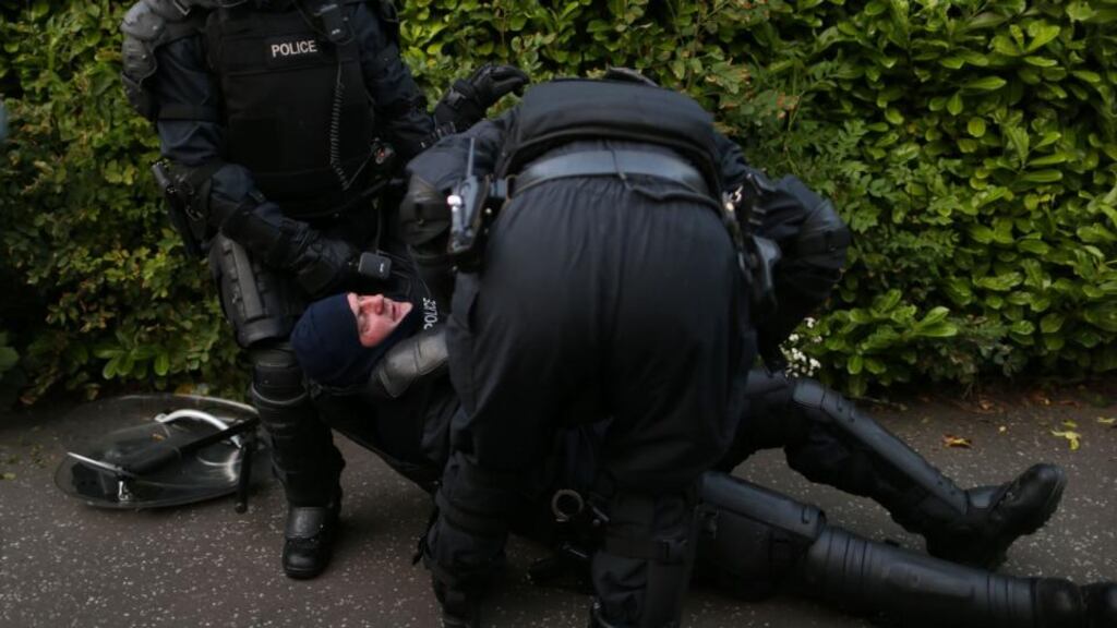 A PSNI Police officer in full riot gear is helped by colleagues after being injured in a confrontation with loyalists in north Belfast, after an Orange July 12th parade was stopped from passing a Nationalist area. Photograph: Julien Behal/PA Wire.