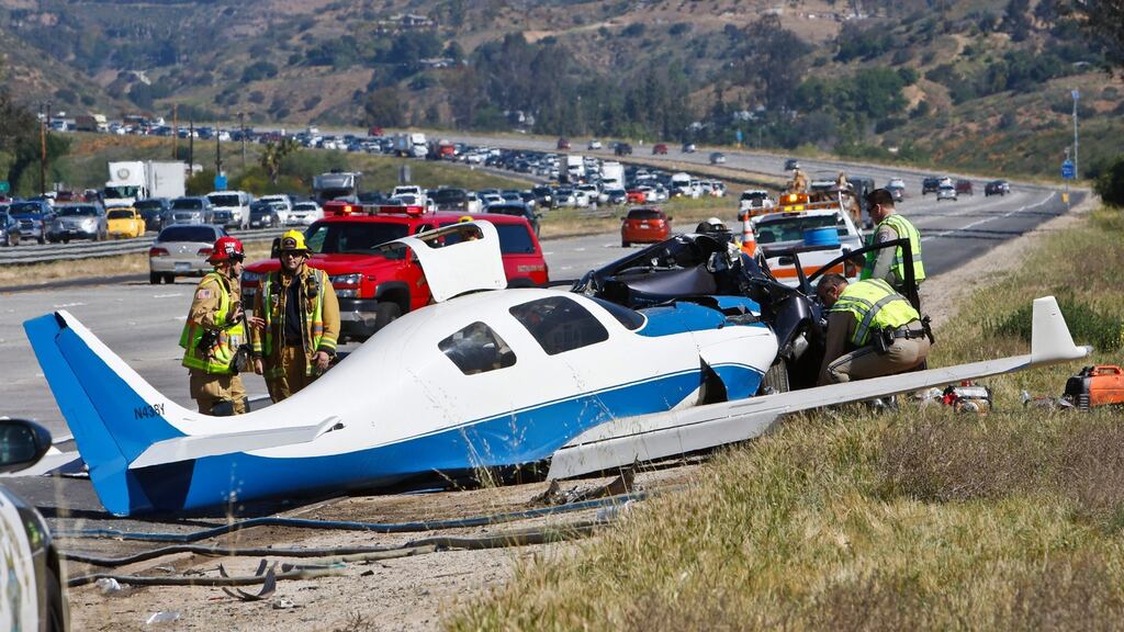 Emergency personnel investigate the scene of a fatal plane crash on a highway in Fallbrook, California. Photograph: Don Boomer/San Diego Union-Tribune/AP