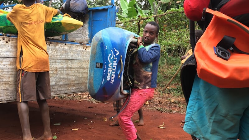 A young boy helps to unload kayaks near the Bujagali dam before the start of the Nile River Festival endurance race, Bujagali. Photograph: Dan Griffin