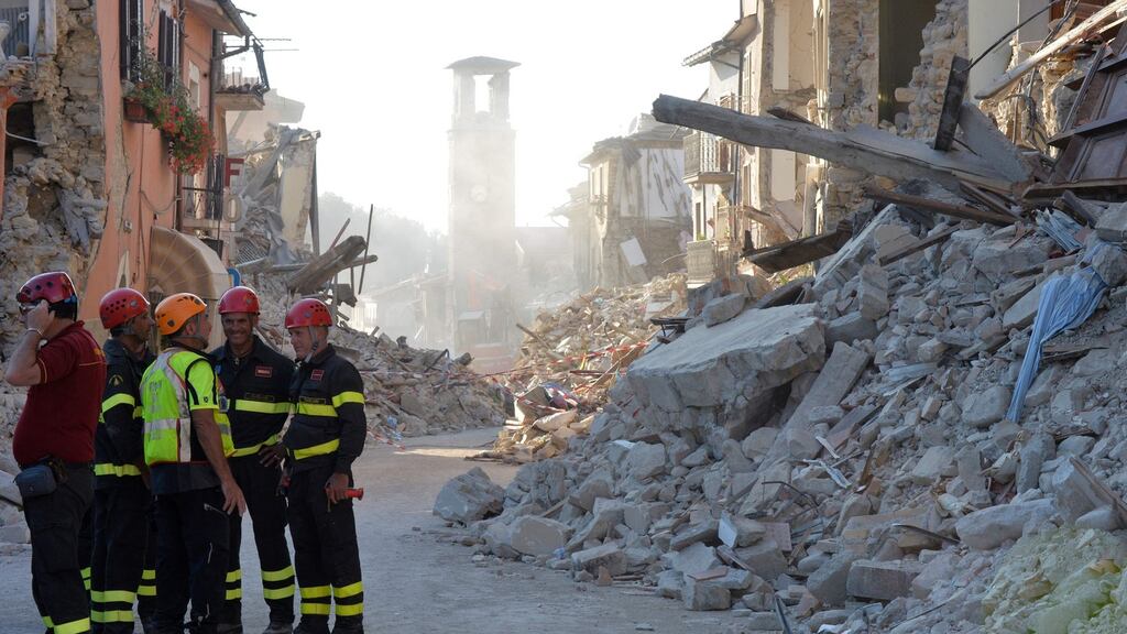 Firefighters and rescue workers stand near the damaged Sant’Agostino church in the central Italian village of Amatrice. Photograph: Andreas Solaro/AFP/Getty Images