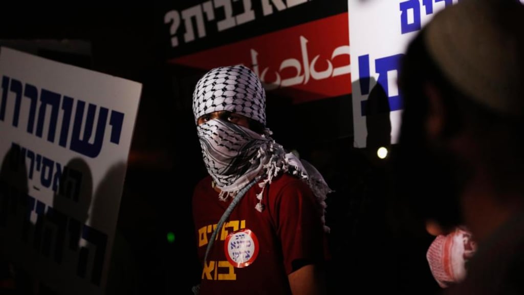 An Israeli protester wears a keffiyeh, a traditional Arab scarf, during a protest against the release of Palestinian prisoners in Israeli jails outside Ofer prison near the West Bank city of Ramallah yesterday. Photograph: Darren Whiteside/Reuters