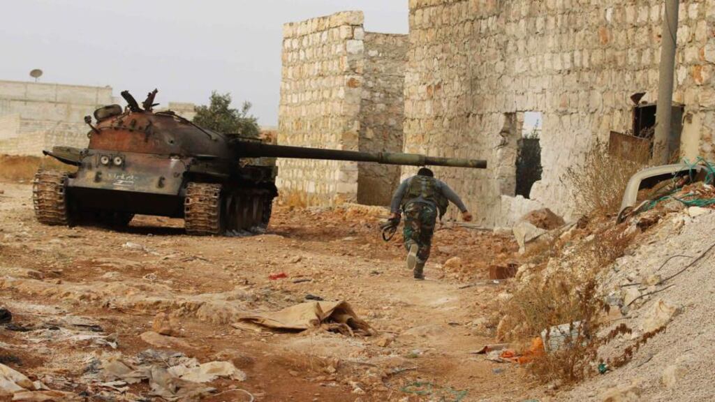 A fighter from Tawhid Brigade, which operates under the Free Syrian Army, runs beside a tank in Base 80 area of Aleppo, yesterday as Syrian forces, backed by Lebanese Hizbullah militants, recaptured an army base in northern Syria from rebels. Photograph:  Molhem Barakat/Reuters.